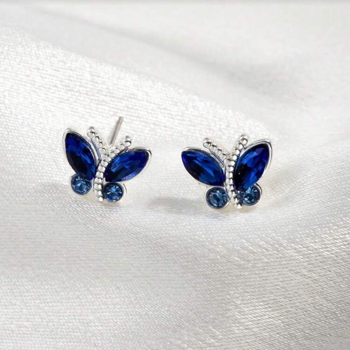 Midnight Blue Butterfly Stud Earrings with blue gemstones on a white background