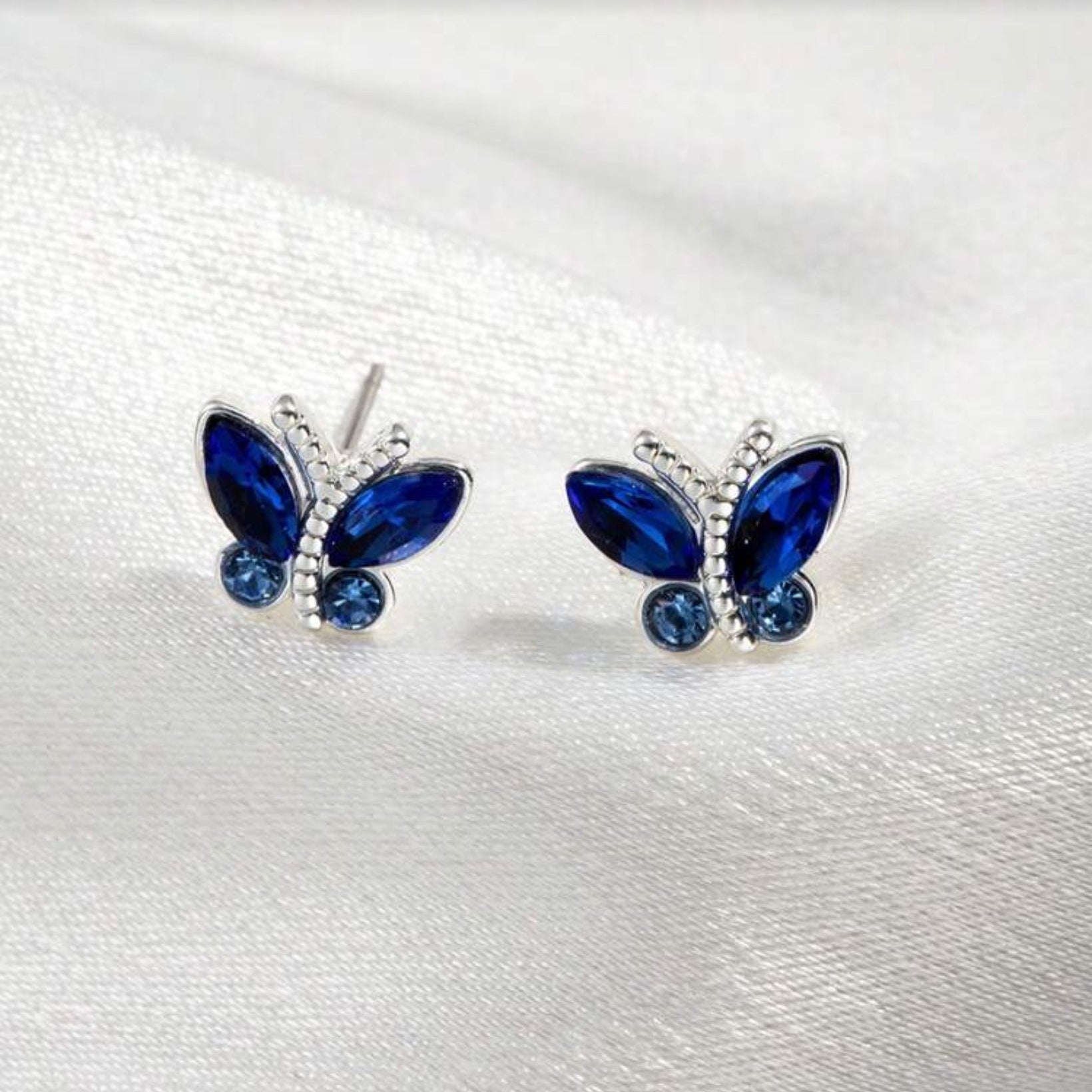 Midnight Blue Butterfly Stud Earrings with blue gemstones on a white background