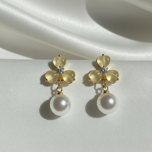 Luminous Gold Clover Pearl Drop Earrings on a satin surface