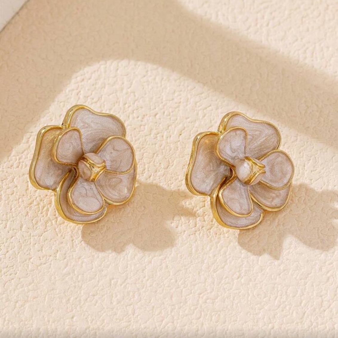 White Enamel Flower Earrings on a textured beige surface