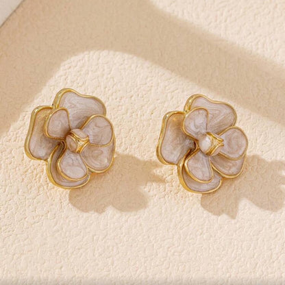 White Enamel Flower Earrings on a textured beige surface