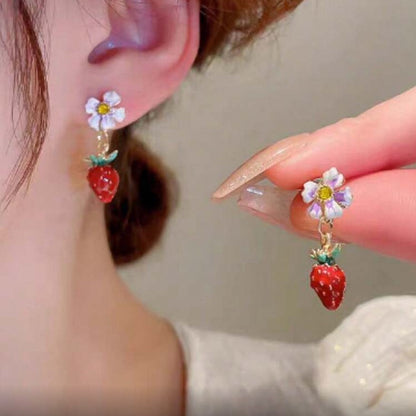 Close-up of a person wearing Blossom Strawberry Drop Earrings with a blurred background