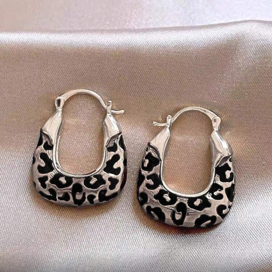 Silver Leopard Hoop Earrings on a light fabric background