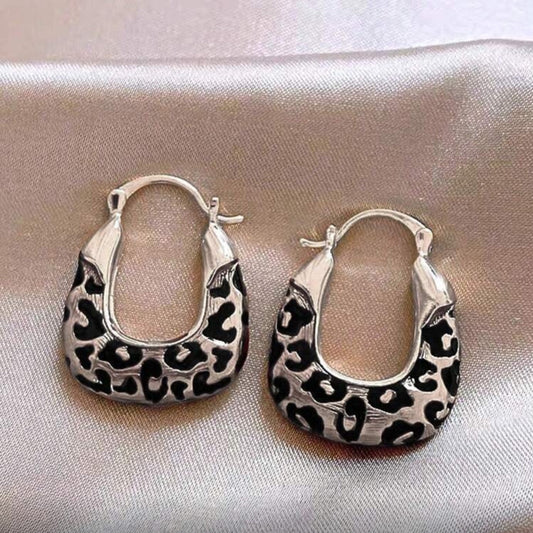 Silver Leopard Hoop Earrings on a light fabric background