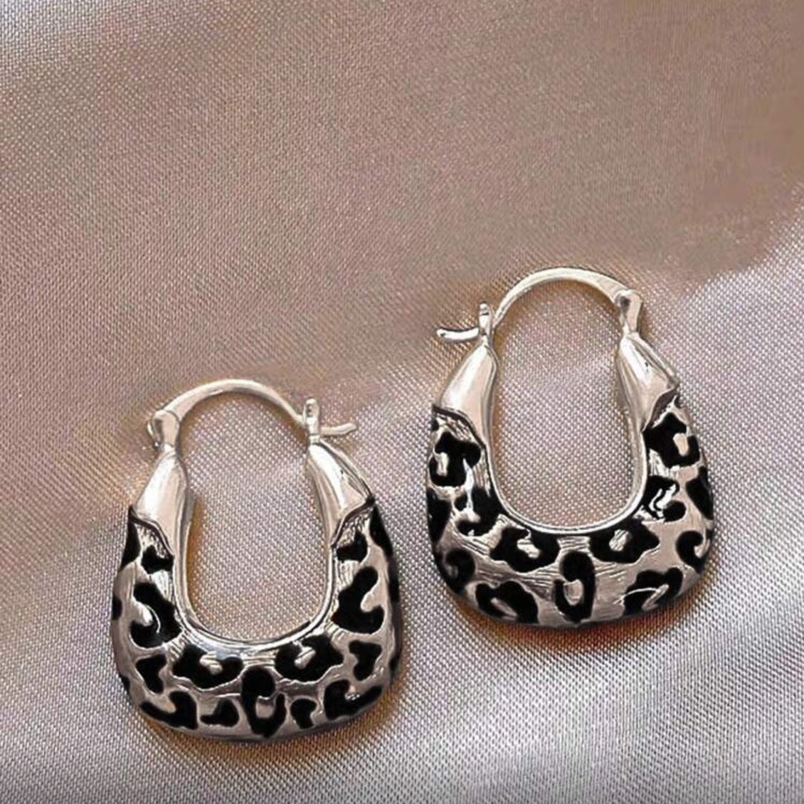 Silver Leopard Hoop Earrings on a metallic surface