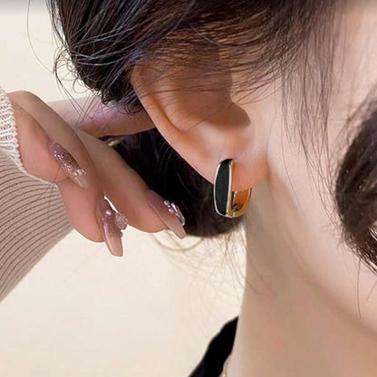 Close-up of a woman wearing Black Enamel Hoop Earrings with a blurred background