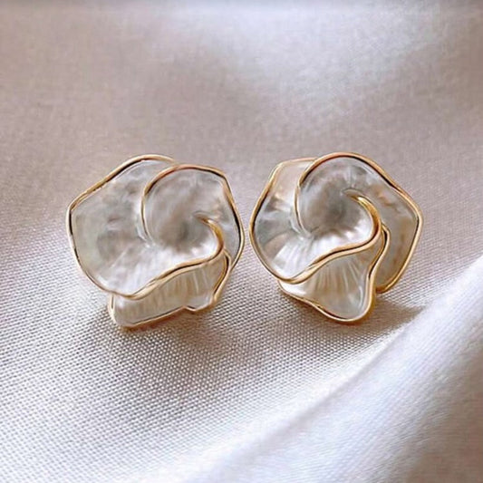 Golden Edge Pearl Earrings with pearl-like petal design and gold trim on a light fabric background