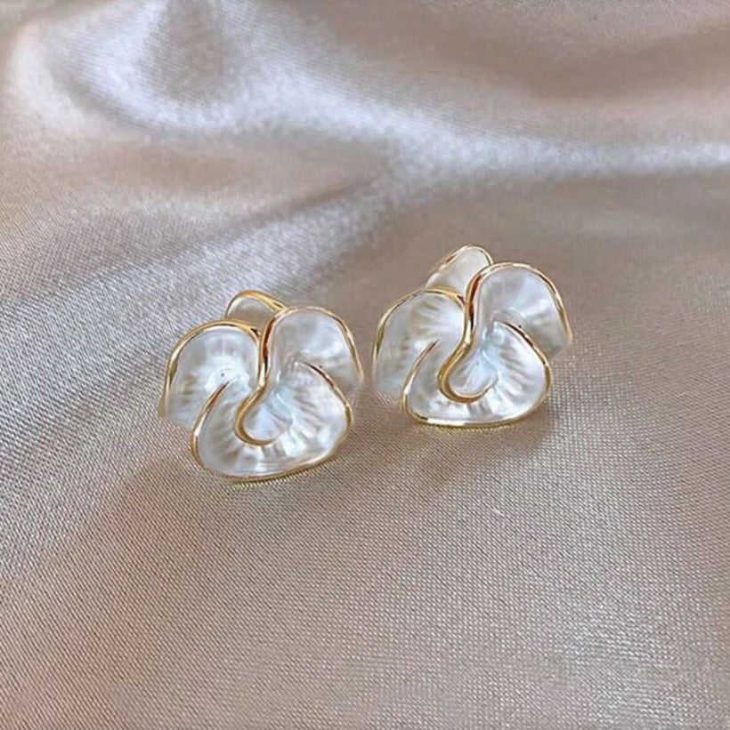 Pair of Golden Edge Pearl Earrings with pearl-like petal design and gold trim on a beige fabric background