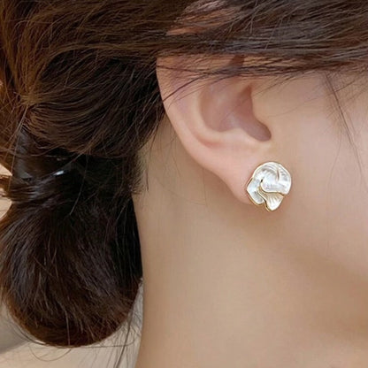 Close-up of Golden Edge Pearl Earrings with pearl-like petal design and gold trim with hair styled in a bun.