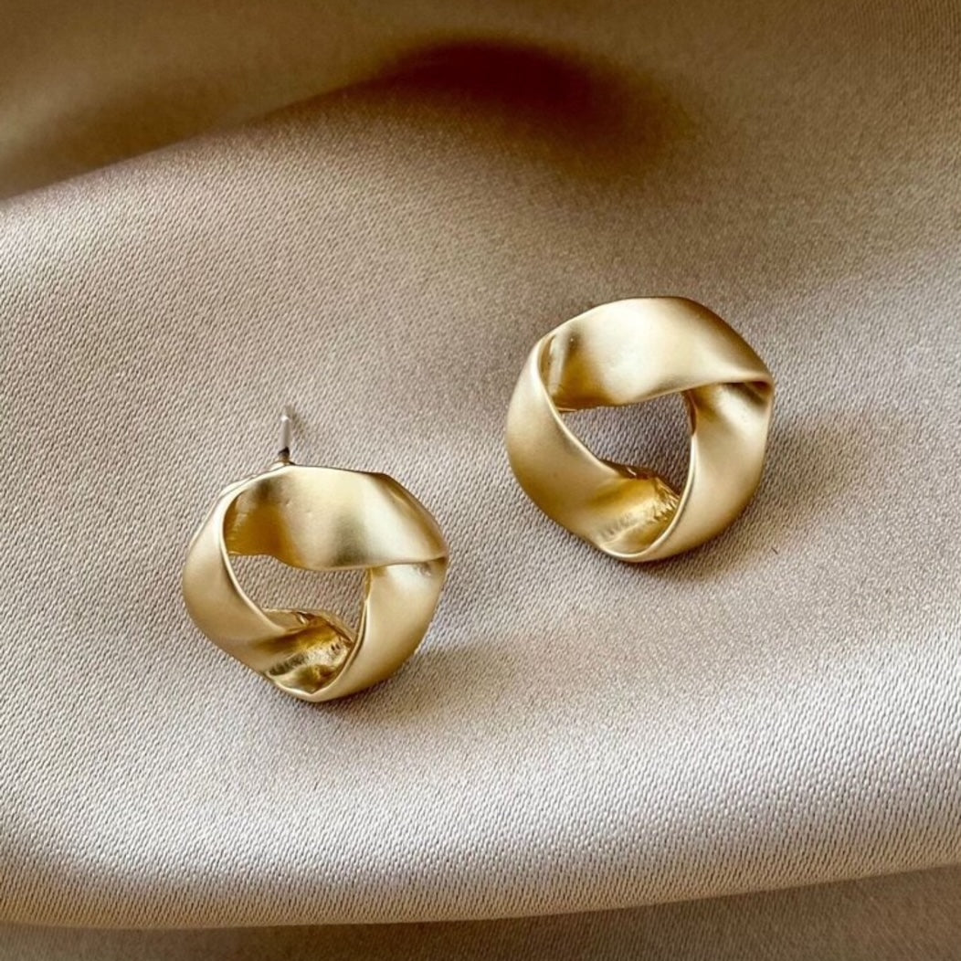satin gold knot earrings on a beige fabric background