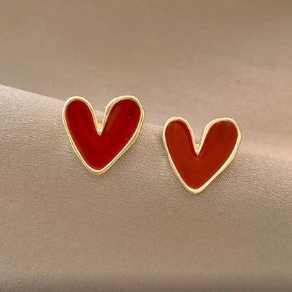 Red Heart Earrings with gold rims on a beige surface