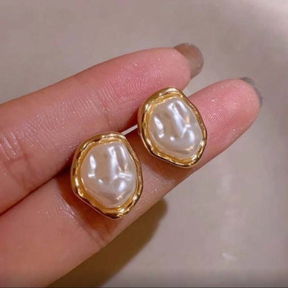Iridescent Glow Pearl Studs held between fingers against a neutral background