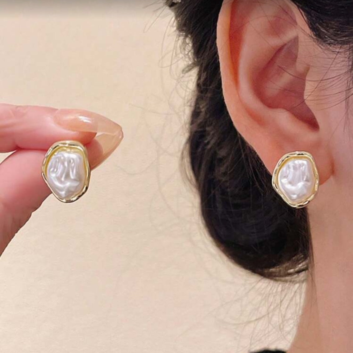 Close-up of a woman wearing Iridescent Glow Pearl Studs held by a hand.