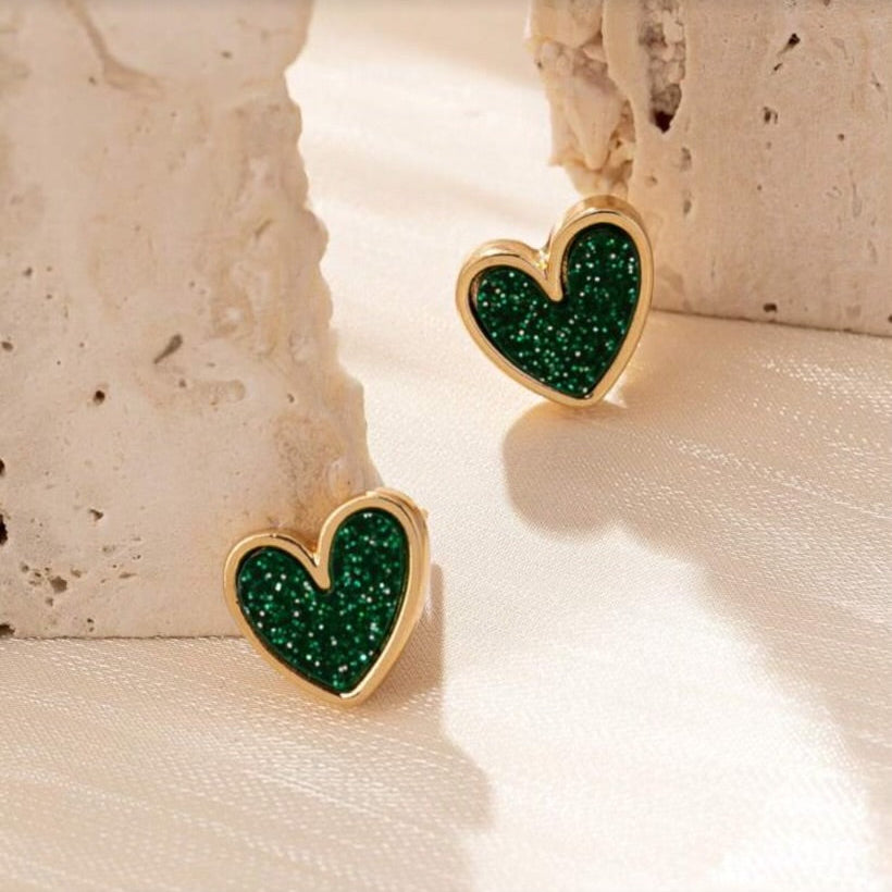 Green Glitter Heart Earrings on a textured beige surface