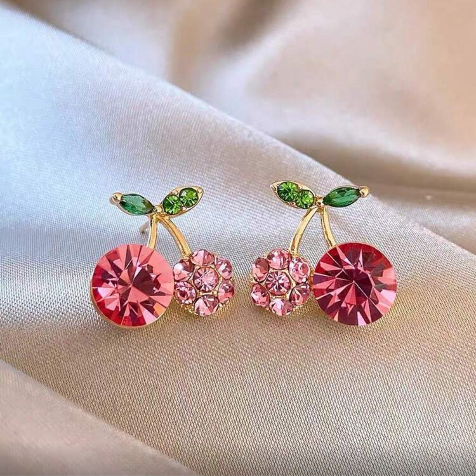 Pink Zircon Cherry earrings with pink gemstones on a soft fabric background