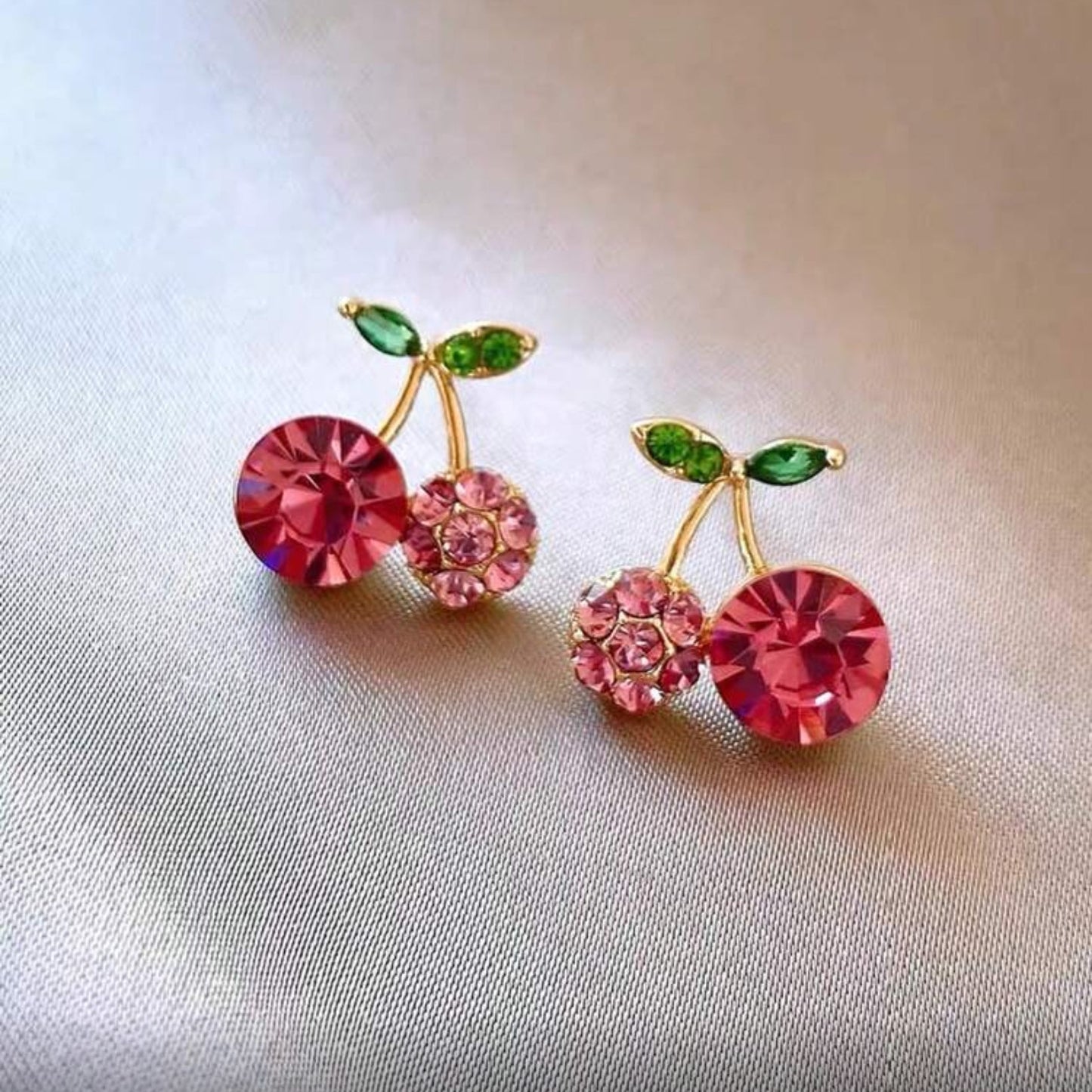 Pink Zircon Cherry earrings with gemstones on a light fabric background
