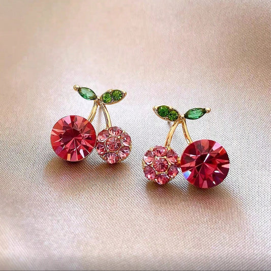 Pink Zircon Cherry earrings with red and green gemstones on a beige background