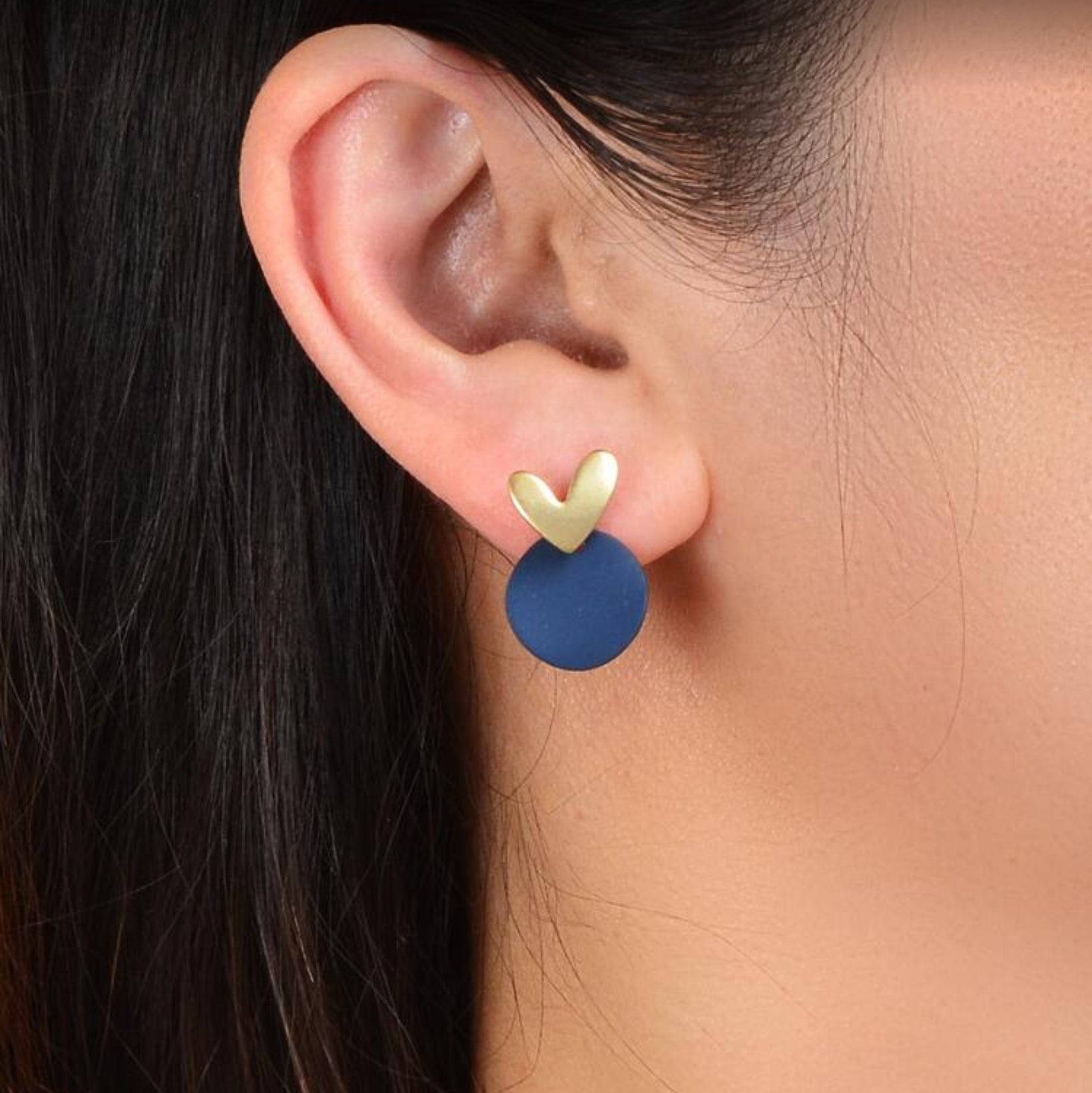 Close-up of a woman wearing Midnight Blue & Gold Heart Earrings with blurred background