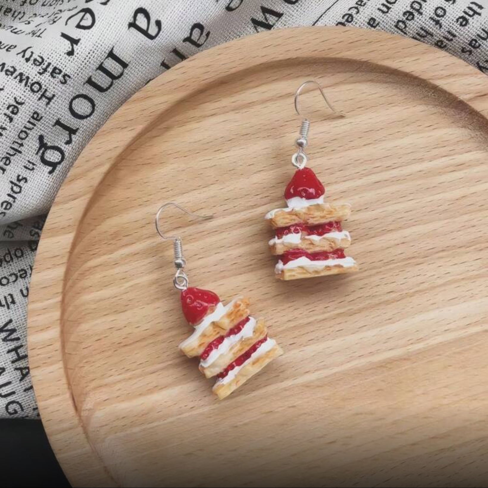 Strawberry Shortcake Layer Earrings on a wooden plate with a newspaper background
