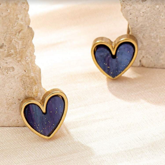 Blue Gold Dust Heart Earrings with purple centers and gold frames on a beige surface.