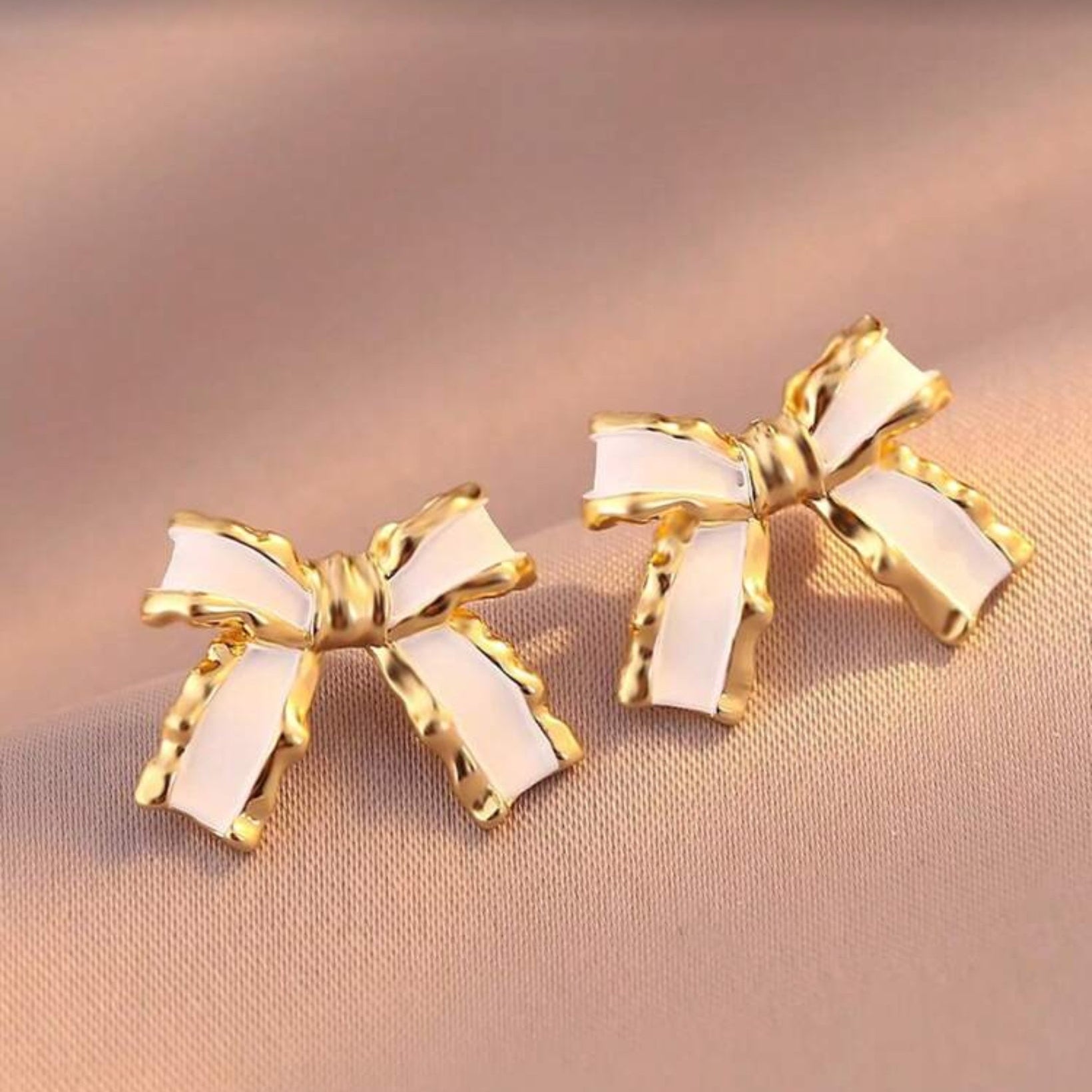White and Gold Bow Earrings on a beige background