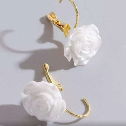 White rose earrings with gold hooks on a light gray background