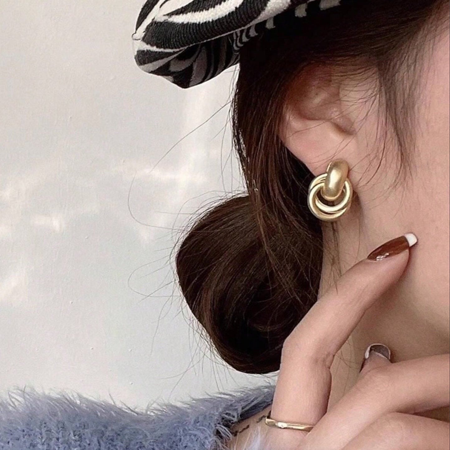 Close-up of a person wearing Satin Gold Hoop Earrings with a blurred background