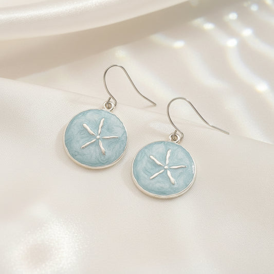 Pair of Seafoam Sand Dollar Earrings with light blue circular stones and silver star designs on a white background