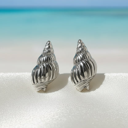 Silver Seashell Earrings on light fabric on a beach