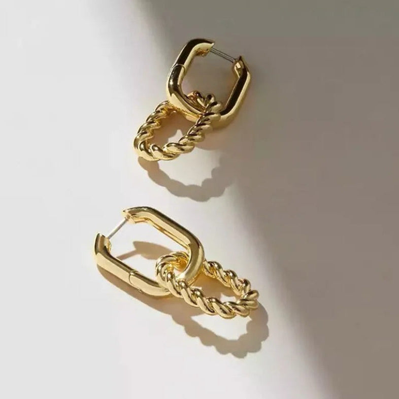 Gold hoop earrings with chain details on a light background