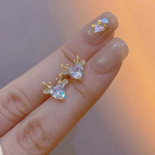 Gold Reindeer Zircon Heart Earrings on a finger with a blurred background