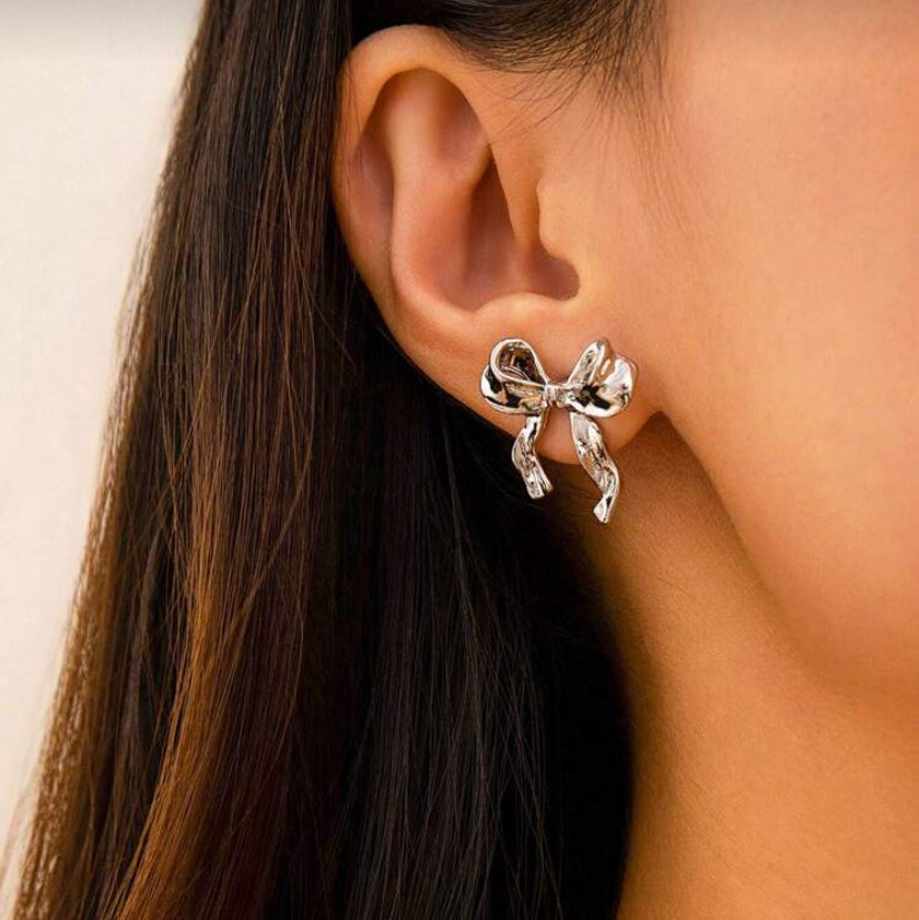 Silver Bow Ribbon Earrings worn by a person with long dark hair.