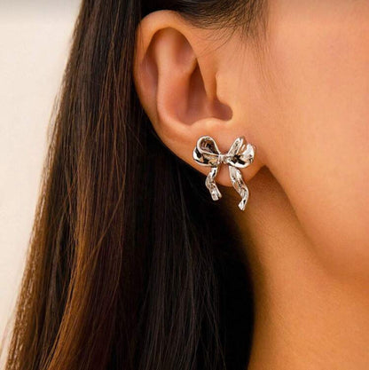 Silver Bow Ribbon Earrings worn by a person with long dark hair.
