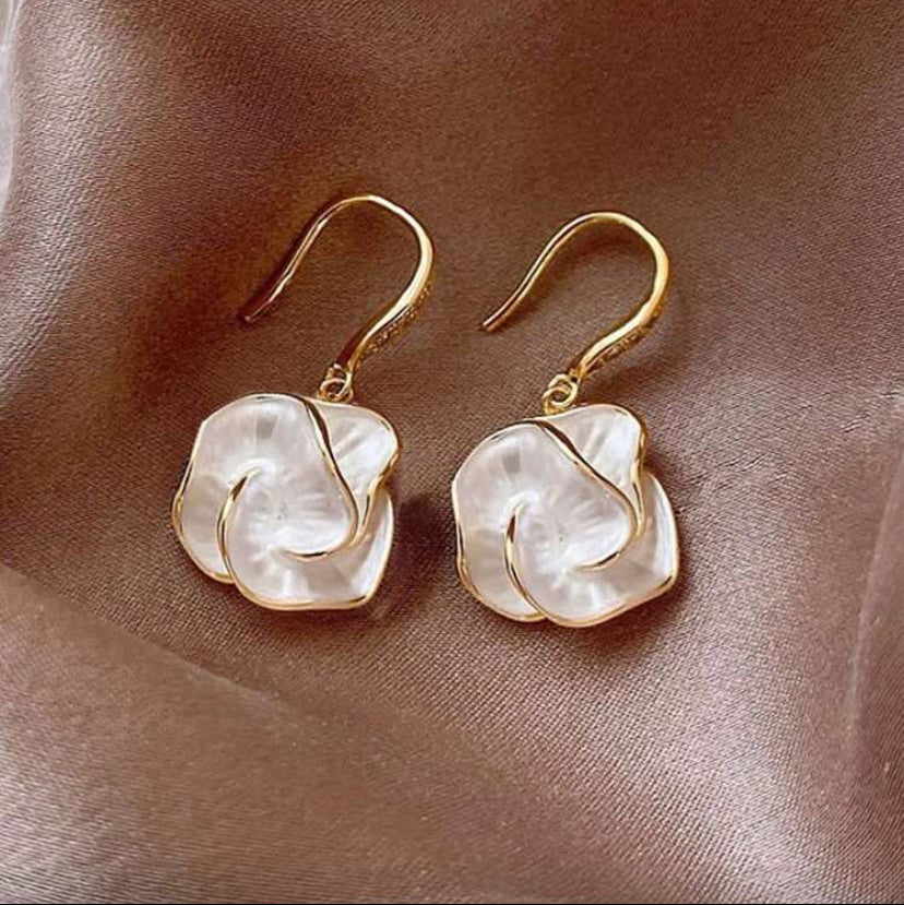 Golden Edge Pearl Drop Earrings with white stone on a brown fabric background