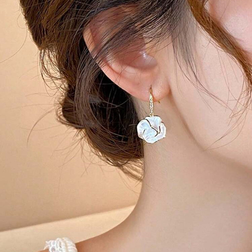 Close-up of a person wearing a Golden Edge Pearl Drop Earring with a soft beige background