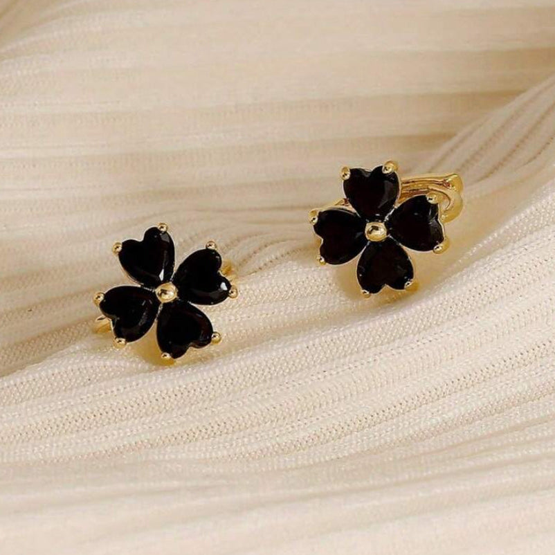 Black Flower Petal Hoop Earrings on a beige fabric background