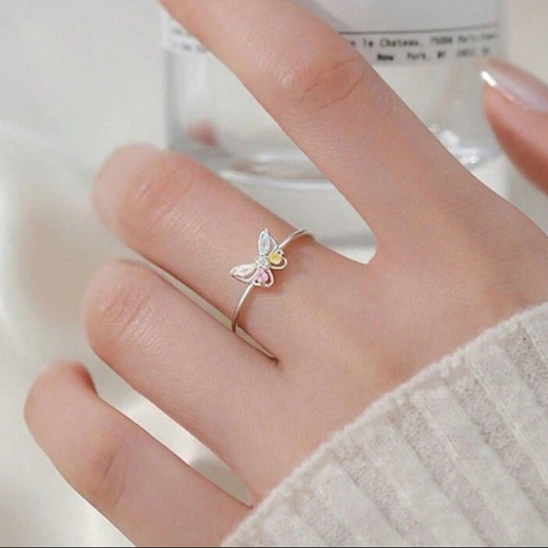 Pastel Butterfly Adjustable Ring on a person's finger with a blurred background
