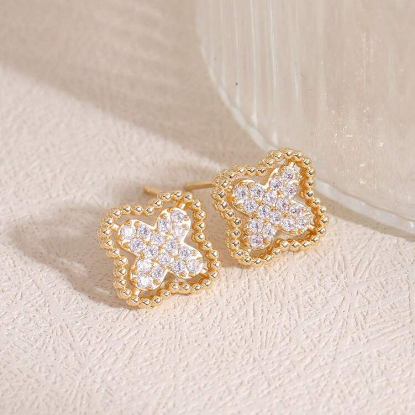 Gold Rhinestone Clover Earrings with clear gemstones on a beige background