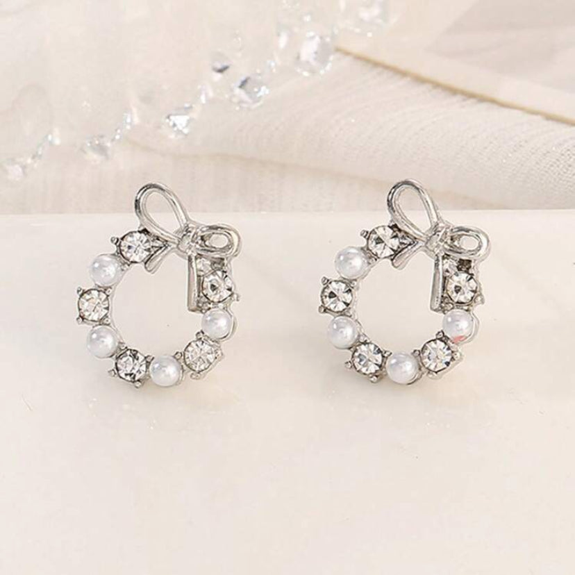Pair of Silver Bow Wreath Earrings with pearls and crystals on a light background