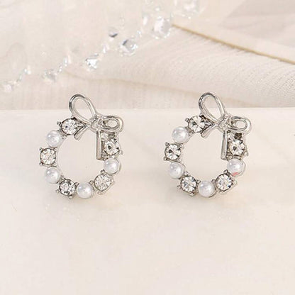 Pair of Silver Bow Wreath Earrings with pearls and crystals on a light background
