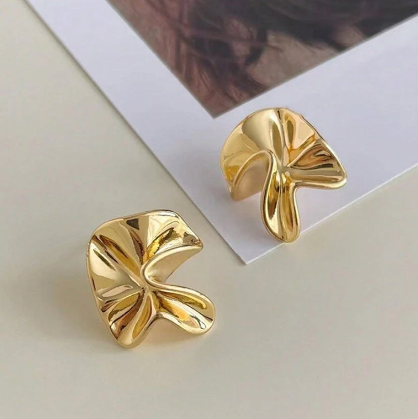 Gold Sculpted Petal Earrings on a light surface with a blurred background