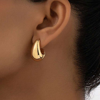 Gold Teardrop Hoop Earrings worn on an ear with a neutral background