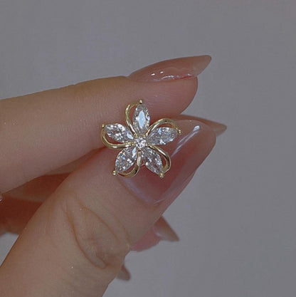 Gold Crystal Flower Earrings with clear gemstones held between fingers against a neutral background