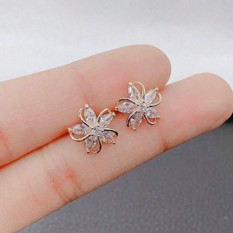 Gold Crystal Flower Earrings held between fingers against a neutral background