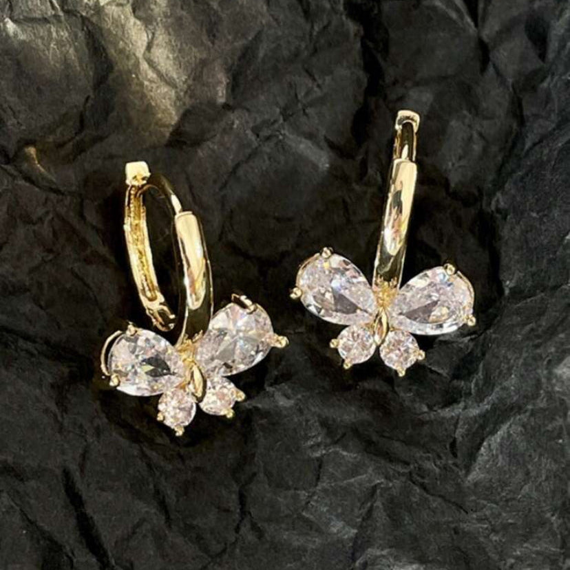 Gold Crystal Butterfly Hoop Earrings with clear gemstones on a black textured background