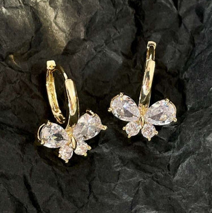 Gold Crystal Butterfly Hoop Earrings with clear gemstones on a black textured background