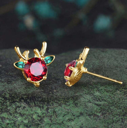 Holiday Red & Green Reindeer Earrings with red gemstones on a green surface