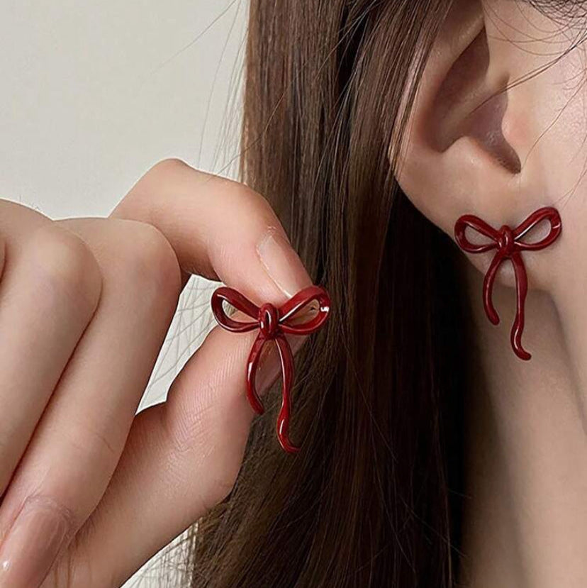 Crimson Bow Earrings worn by a person with a neutral background