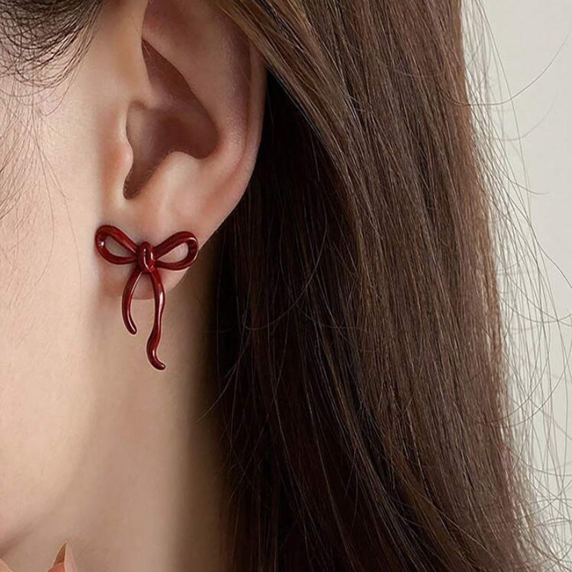 Close-up of an ear wearing a Crimson Bow Earrings with blurred background
