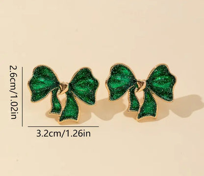 Emerald Glitter Bow Earrings with gold accents on a beige background